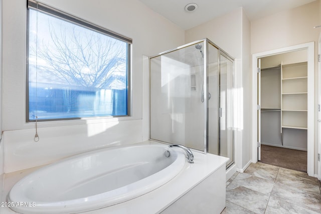 bathroom featuring a stall shower, a walk in closet, and a bath