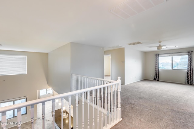 hall with baseboards, visible vents, carpet flooring, and an upstairs landing