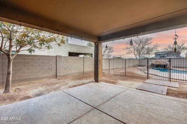 patio terrace at dusk with a fenced in pool