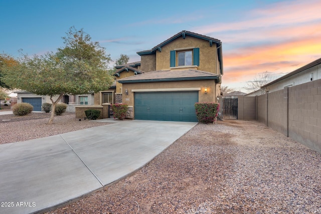 traditional-style house with concrete driveway, a tiled roof, a gate, fence, and stucco siding