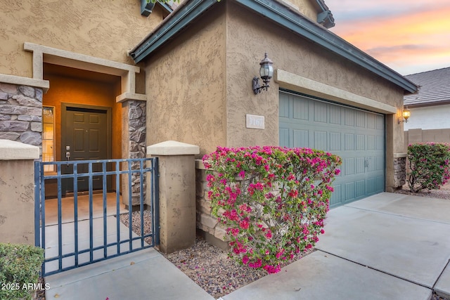 doorway to property with a garage, stone siding, fence, and stucco siding