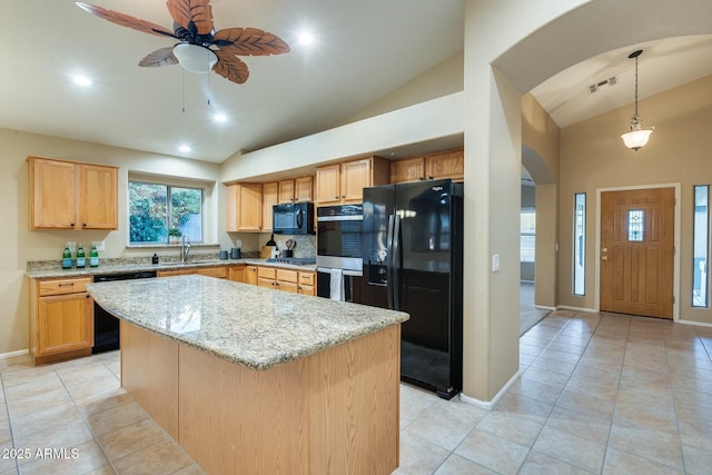 kitchen with light tile patterned flooring, a kitchen island, hanging light fixtures, light stone counters, and black appliances