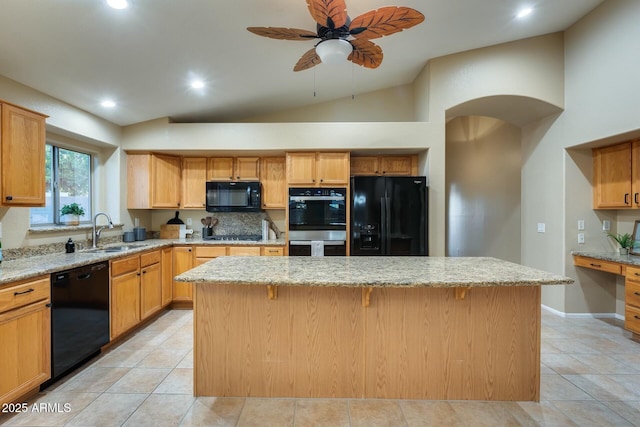 kitchen with sink, light stone counters, black appliances, a kitchen island, and vaulted ceiling