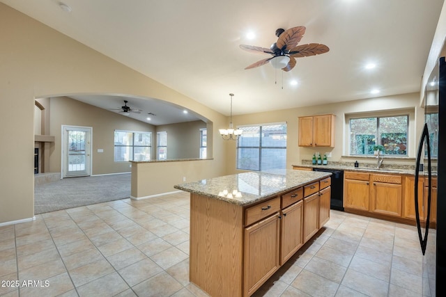 kitchen with a center island, a fireplace, light stone countertops, decorative light fixtures, and vaulted ceiling