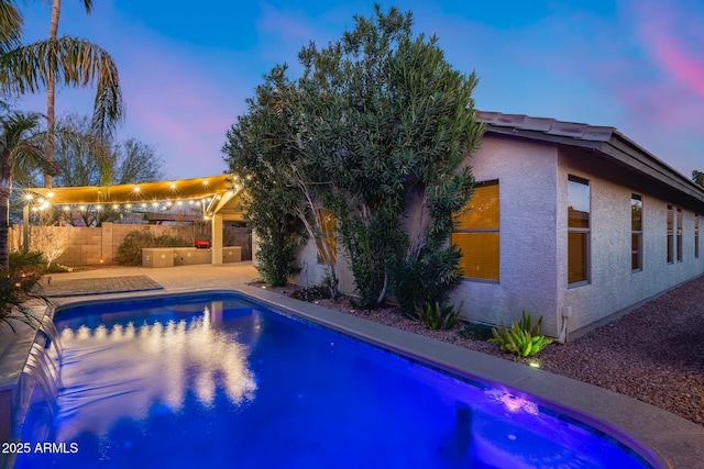 pool at dusk featuring a patio