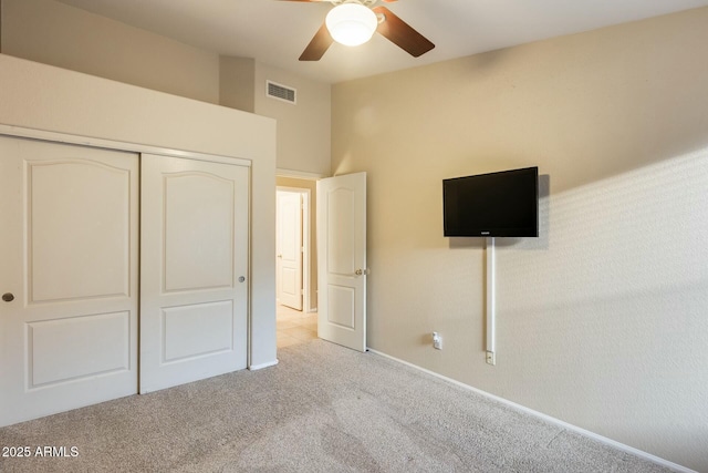 unfurnished bedroom with ceiling fan, a closet, vaulted ceiling, and light carpet