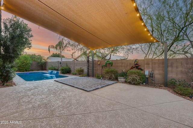 patio terrace at dusk with a fenced in pool and pool water feature