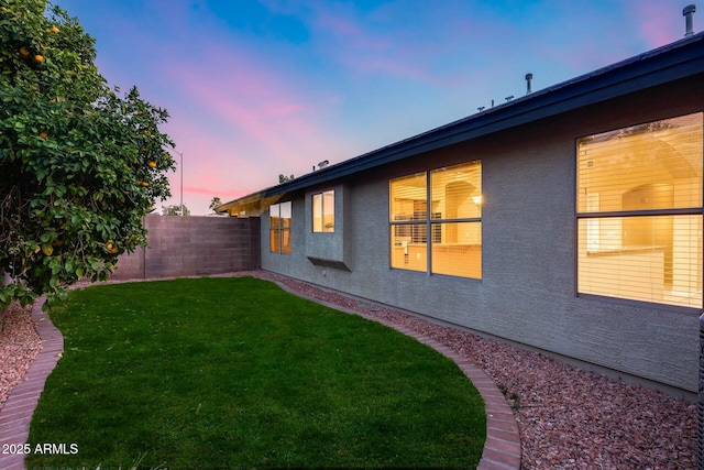 property exterior at dusk with a lawn