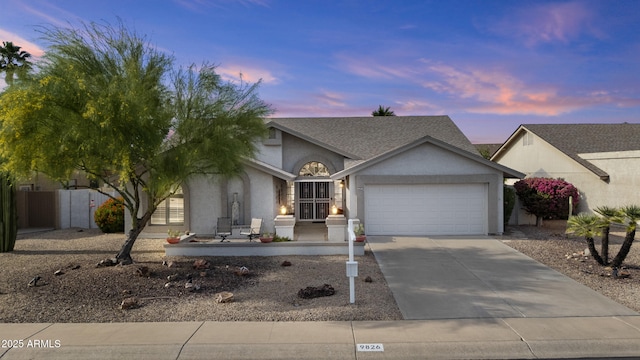 view of front of home featuring fence, roof with shingles, an attached garage, stucco siding, and concrete driveway