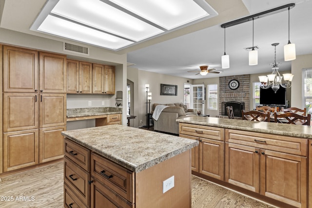 kitchen featuring visible vents, a fireplace, light wood-style floors, open floor plan, and a center island