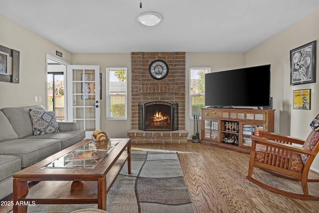 living room with a brick fireplace and wood finished floors