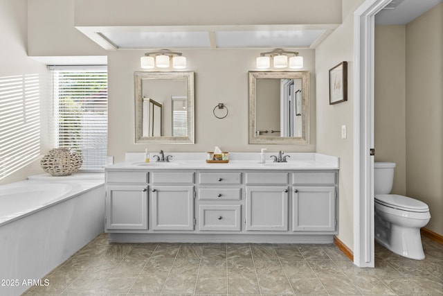 bathroom with a sink, a garden tub, toilet, and double vanity