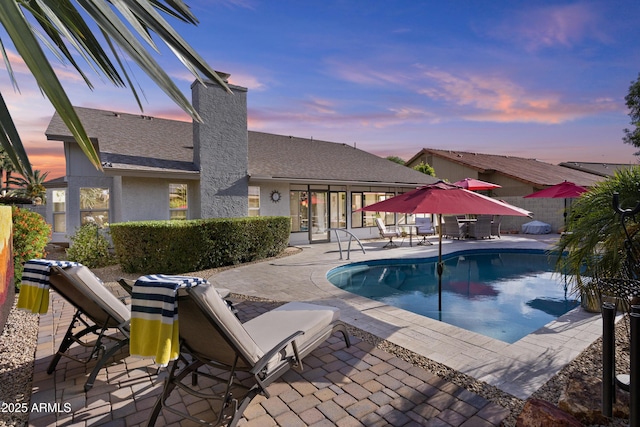 pool at dusk with fence, a patio area, and a fenced in pool