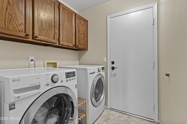 washroom featuring cabinet space and washer and clothes dryer