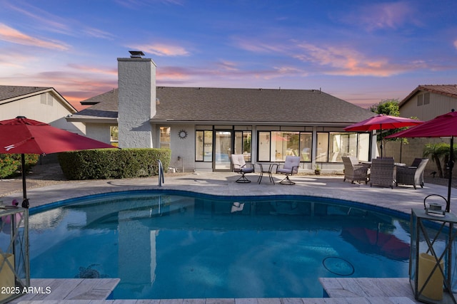 pool at dusk featuring a patio and a fenced in pool