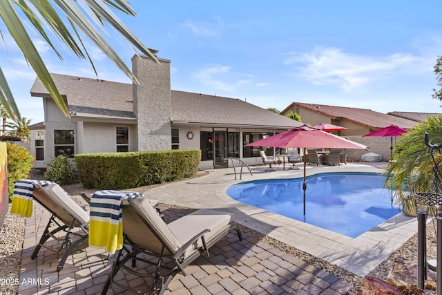 view of pool with fence, outdoor dining space, a sunroom, a fenced in pool, and a patio
