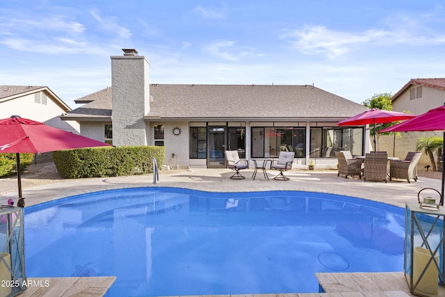 outdoor pool with a sunroom and a patio area