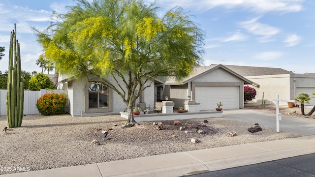 view of front of home with concrete driveway, an attached garage, fence, and stucco siding
