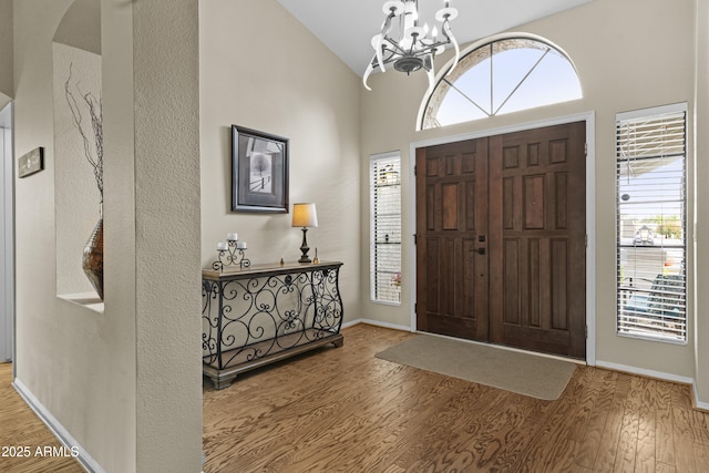 foyer entrance with an inviting chandelier, a healthy amount of sunlight, and wood finished floors