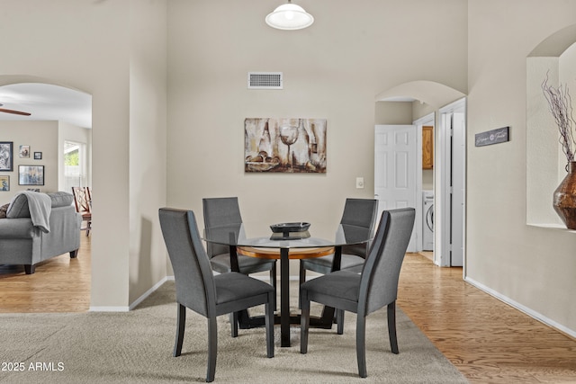 dining room with arched walkways, a high ceiling, visible vents, and baseboards