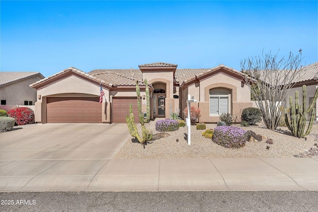 mediterranean / spanish house featuring stucco siding, concrete driveway, a tile roof, and a garage