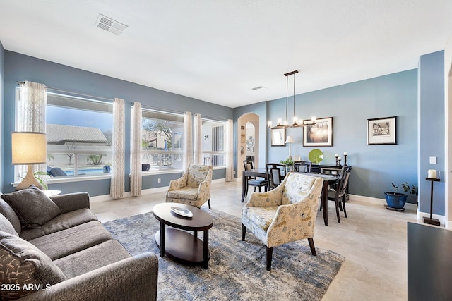 living room with arched walkways, visible vents, and baseboards