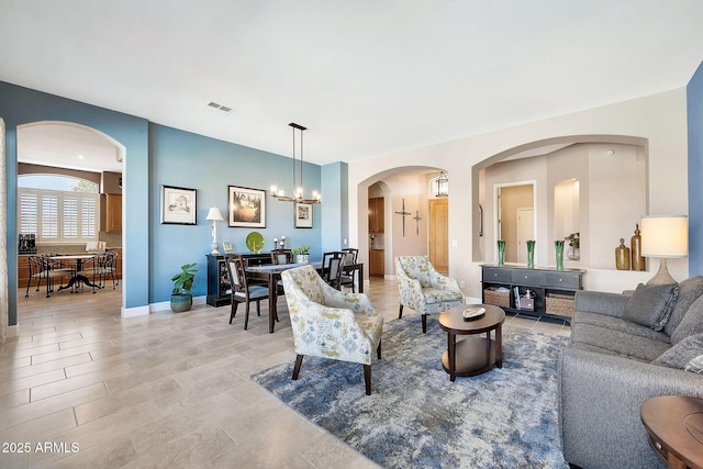 living room featuring baseboards, visible vents, and a chandelier