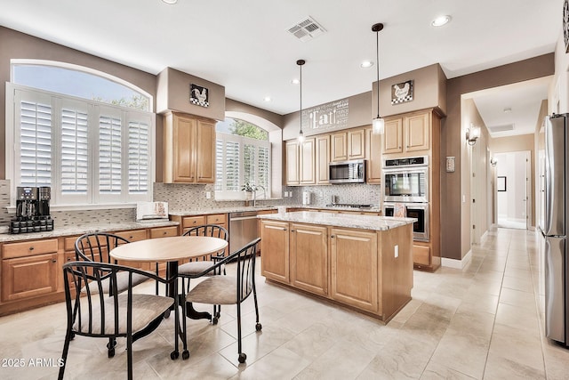 kitchen with tasteful backsplash, visible vents, a center island, appliances with stainless steel finishes, and a sink