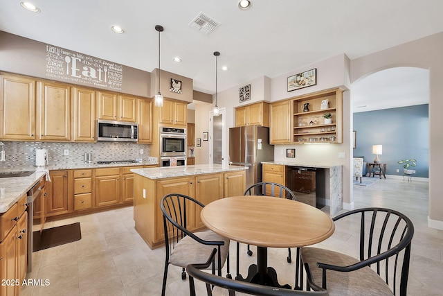 kitchen with visible vents, a sink, a center island, appliances with stainless steel finishes, and decorative backsplash