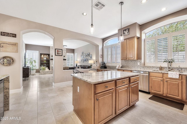 kitchen featuring light stone counters, visible vents, a kitchen island, dishwasher, and tasteful backsplash