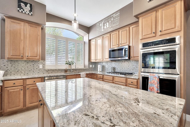 kitchen featuring light stone counters, light brown cabinetry, a sink, appliances with stainless steel finishes, and backsplash