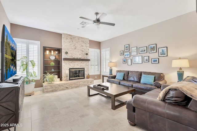 living room with plenty of natural light, a fireplace, a ceiling fan, and visible vents