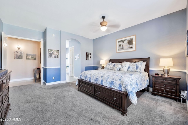 bedroom featuring baseboards, carpet floors, arched walkways, and ceiling fan