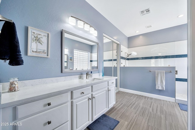 bathroom featuring visible vents, a walk in shower, vanity, and baseboards