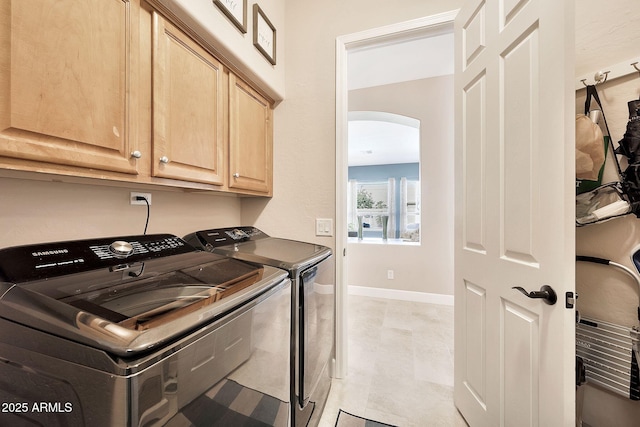 laundry room with arched walkways, cabinet space, washer and dryer, and baseboards