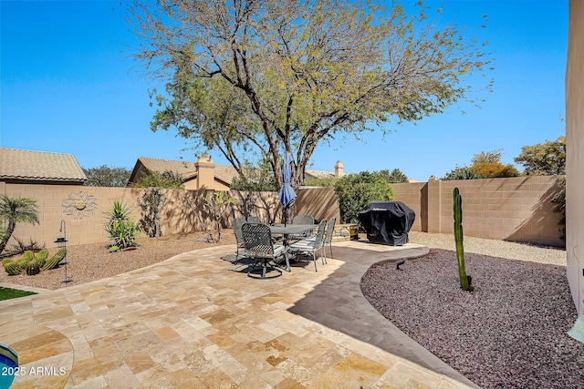 view of patio with grilling area, a fenced backyard, and outdoor dining space