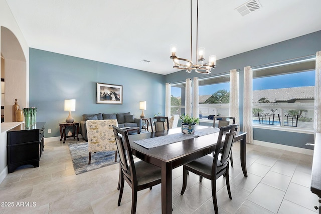 dining space featuring an inviting chandelier, arched walkways, visible vents, and baseboards