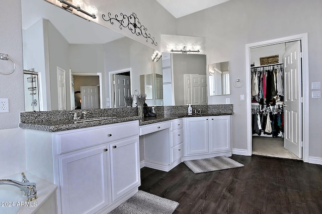 bathroom with wood-type flooring, vanity, and high vaulted ceiling