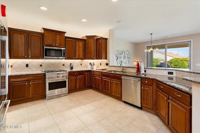 kitchen with a notable chandelier, stainless steel appliances, stone counters, and sink