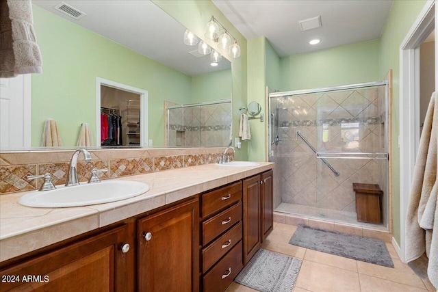 bathroom featuring vanity, a shower with shower door, tile patterned flooring, and decorative backsplash