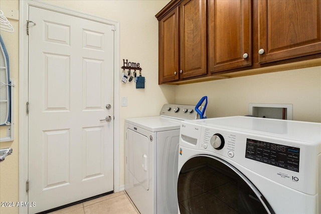 washroom featuring cabinets, light tile patterned floors, and washing machine and dryer