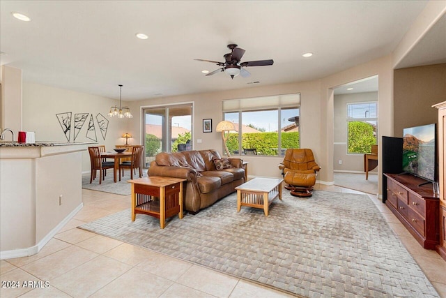 tiled living room with ceiling fan with notable chandelier