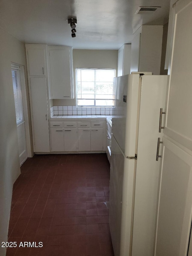 kitchen with white refrigerator and white cabinets