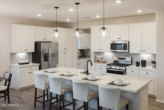 19022 W Rose Ln, Waddell, AZ 85355 - kitchen with white cabinets, a sink, stainless steel appliances, and a breakfast bar area