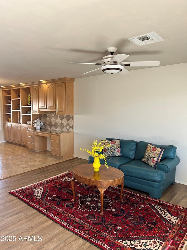 living room featuring ceiling fan, built in desk, and light hardwood / wood-style floors