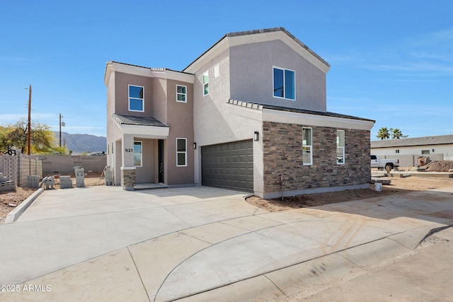 traditional home with driveway, stone siding, fence, a mountain view, and stucco siding