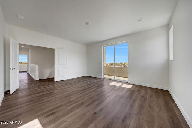 empty room with dark wood-type flooring and baseboards