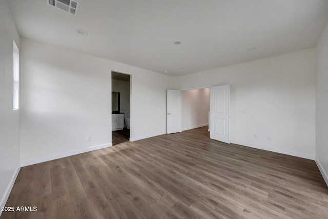 unfurnished room featuring visible vents, baseboards, and wood finished floors