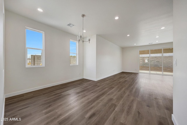 unfurnished room with dark wood-style floors, visible vents, a notable chandelier, and baseboards