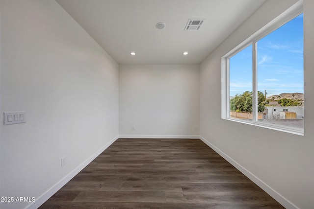 spare room featuring recessed lighting, dark wood-style flooring, visible vents, and baseboards